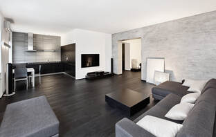 Picture of a clean living are with grey couches and gray colored flooring.